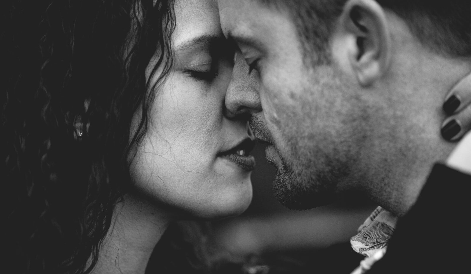 grayscale photo of man and woman kissing each other